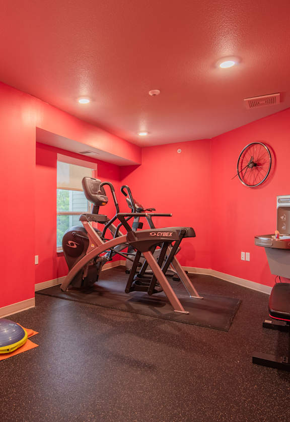 A red room with a gym set up including weights and a bench press.