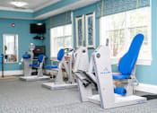 Thumbnail 10 of 17 - A gym with blue chairs and a leg press machine.