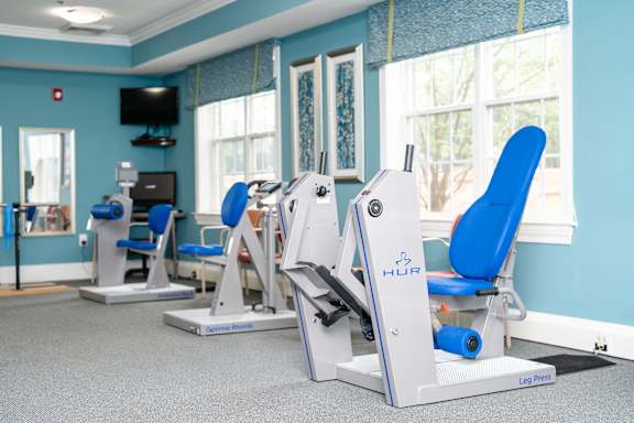 A gym with blue chairs and a leg press machine.