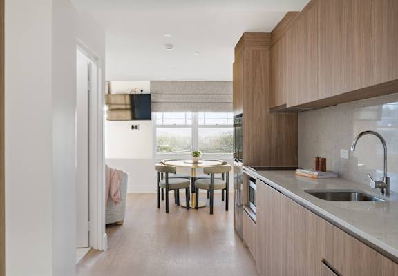 A modern kitchen with wooden cabinets and a dining table with chairs.