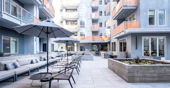 A patio with a table and chairs and umbrellas.