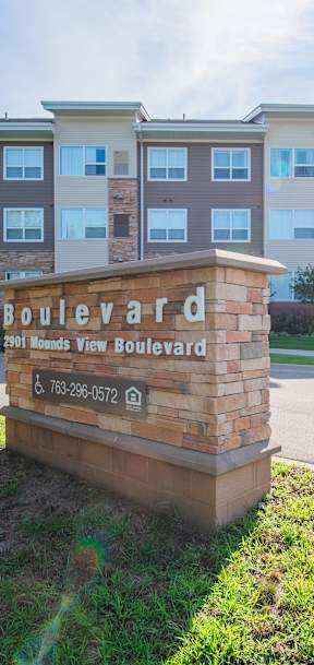 A sign for Boulevard Apartments stands in front of a building.