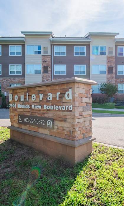 A sign for Boulevard Apartments stands in front of a building.