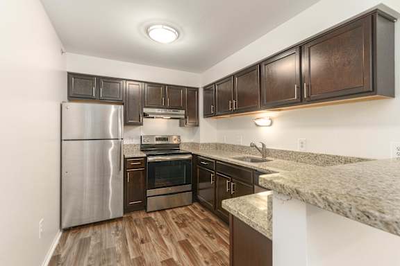 A kitchen with a refrigerator, oven, and sink.