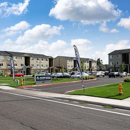 a street with an apartment complex with cars parked in front of it