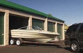 A boat is parked in front of a green building.