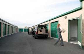 A woman walks down a long hallway between storage units.