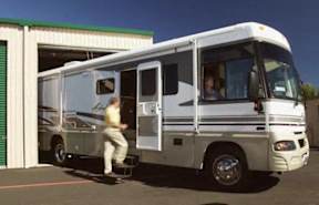 A white RV is parked outside a building with a man stepping out.