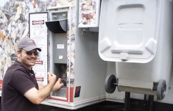A man is opening a compartment in a large white appliance.