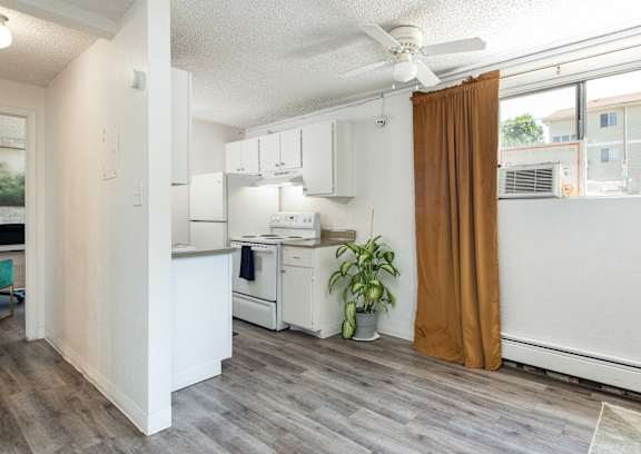 a small kitchen with a ceiling fan and a curtain