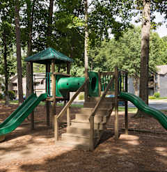 A playground with a green slide and wooden structure at Austin Chase Apartments, Macon, 31210