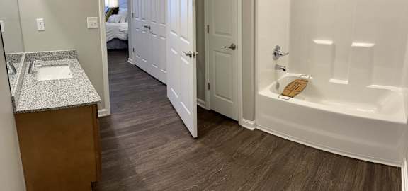 a bathroom with a tub and a sink and a doorway to a bedroom