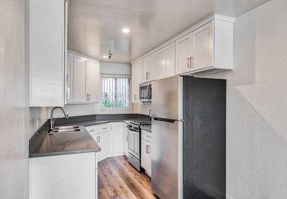 a kitchen with white cabinets and a stainless steel refrigerator