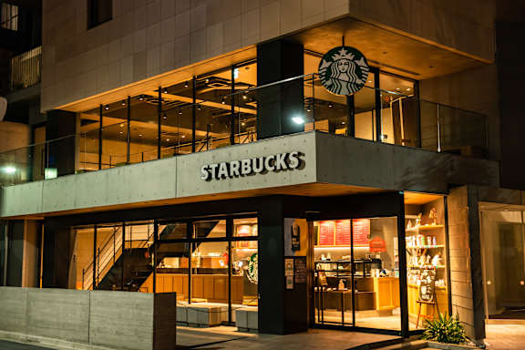 A Starbucks storefront at night with lights on inside.