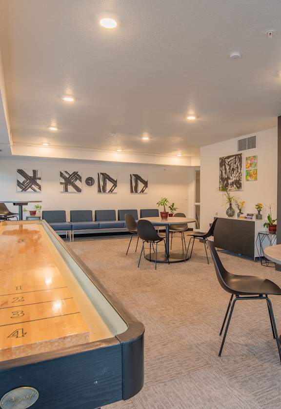 A room with a pool table and chairs.