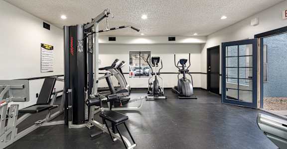 A gym with a variety of equipment including a treadmill, a stationary bike, and a weight machine.