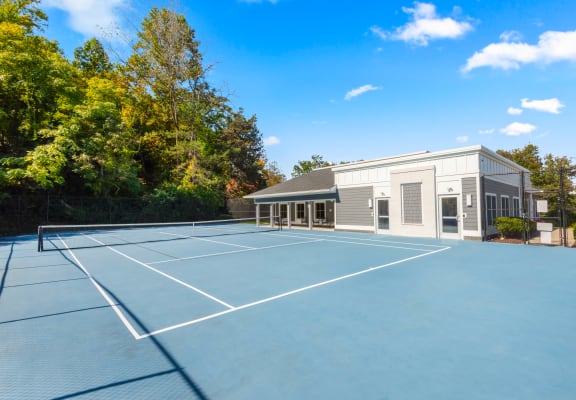 a large tennis court in front of a house with a tennis court