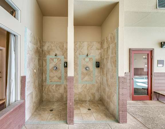 two showers in a bathroom with a window and a door