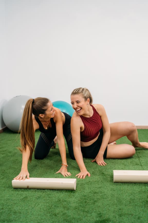 two women doing yoga on the grass with weights