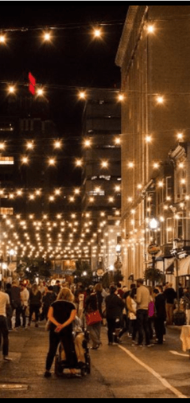 a crowd of people walking down a city street at night