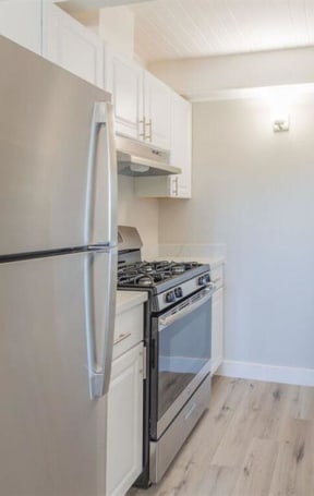 a kitchen with white cabinets and a stainless steel refrigerator  at The Preston at Hillsdale, San Mateo, CA
