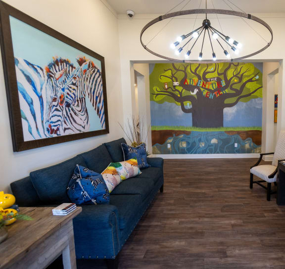a living room with a blue couch and a painting on the wall