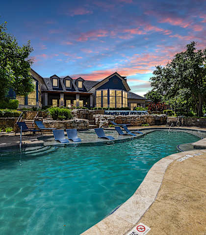 a swimming pool with a house in the background at sunset at The Vista on Brodie, Austin