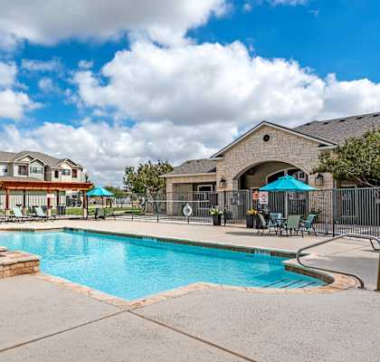 A swimming pool surrounded by a fence and a building in the background.