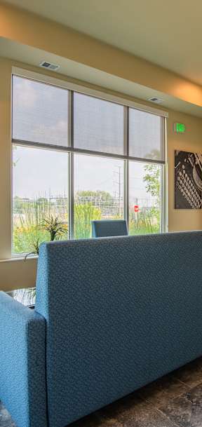 A blue couch sits in a room with a chair and a window.