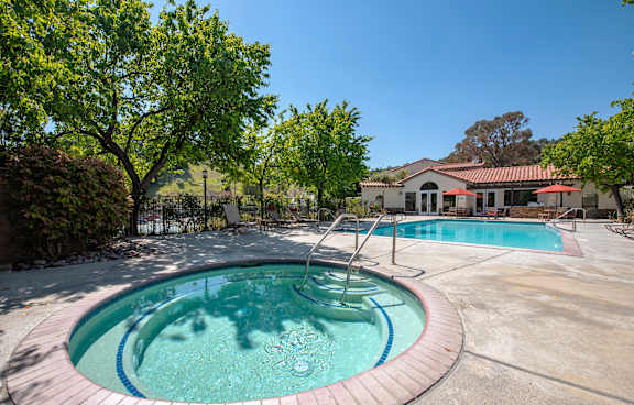 A swimming pool surrounded by a metal fence and chairs.