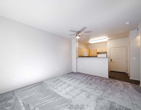 an empty living room with white walls and a ceiling fan