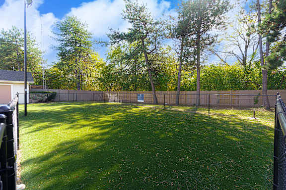 the backyard has a fenced in area with grass and trees at AVIA Lofts on Victors Way, Ann Arbor, MI 48108