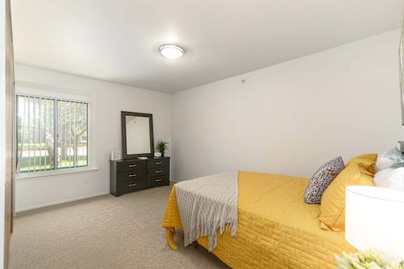 A bedroom with a bed, dresser, and mirror.