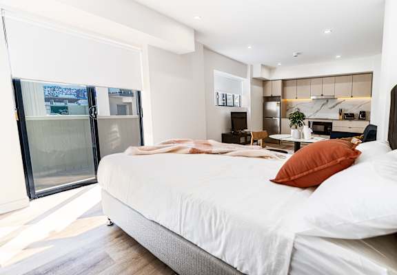 a bedroom with a large bed and a kitchen with a sliding glass door