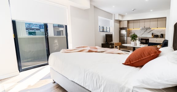 a bedroom with a large bed and a kitchen with a sliding glass door