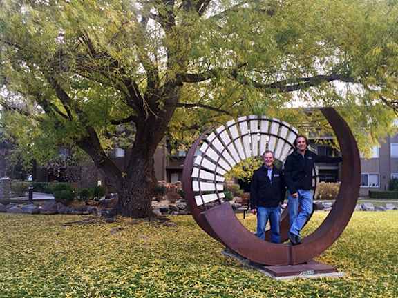 a couple of people standing in front of a sculpture