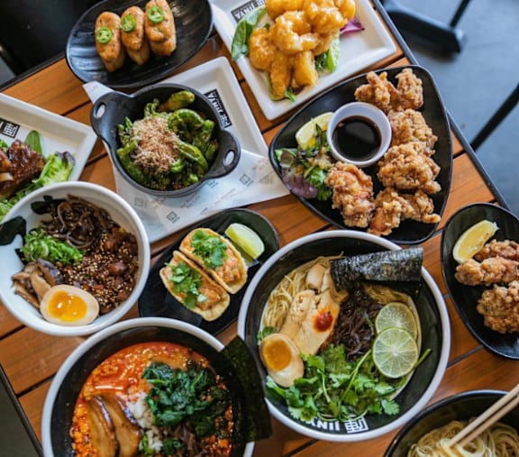 A variety of Asian dishes are displayed on a wooden table.