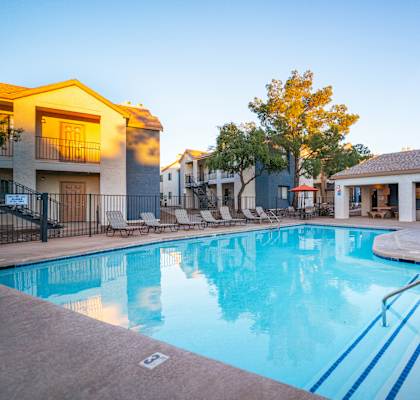 A swimming pool surrounded by a fence and chairs.