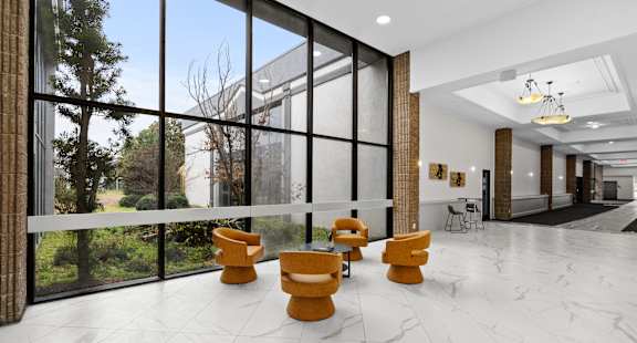 A spacious lobby with yellow chairs and a marble floor.