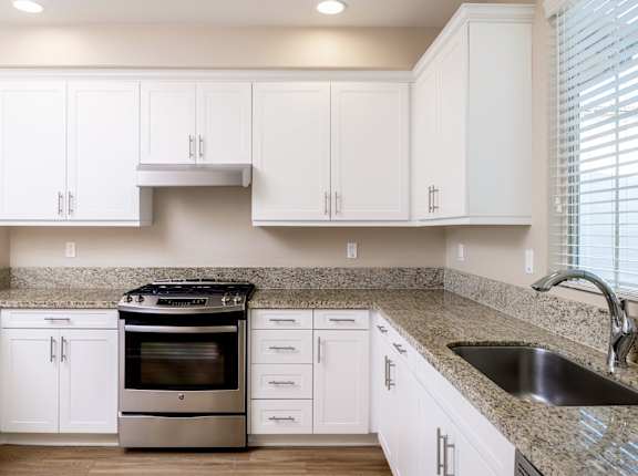 A kitchen with white cabinets and a granite countertop.