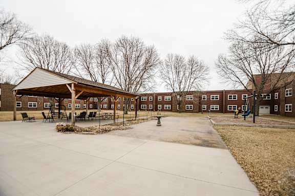 A playground area in front of a building with a brown roof.
