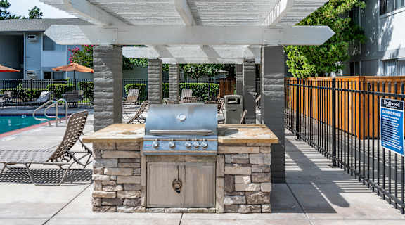 a barbecue grill in the backyard of a house with a pool