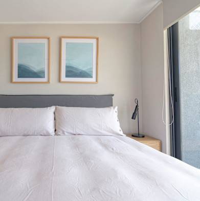 a bedroom with a white bed and two pictures on the wall
