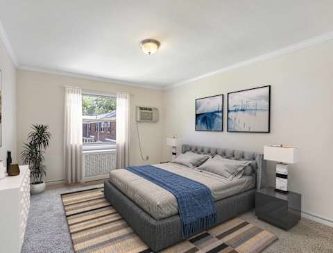 A bedroom with a large bed and two framed pictures on the wall. at Lakeview Apartments, Leonia, New Jersey