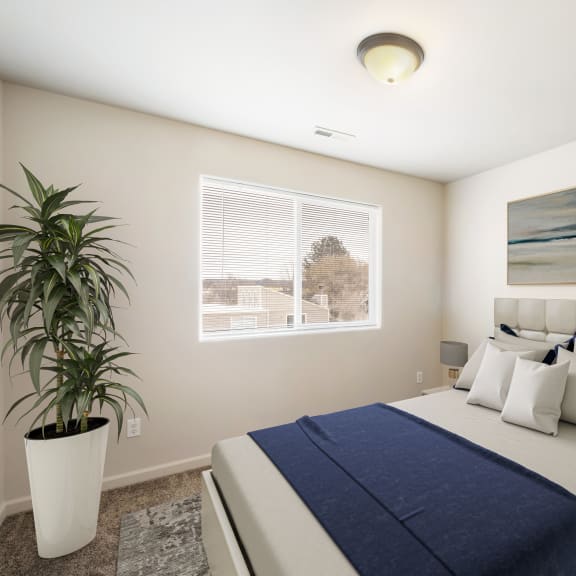 White and blue bed in an open bedroom with a window at Pine Tree Park Apartments in Kennewick WA at Pine Tree Park, Kennewick