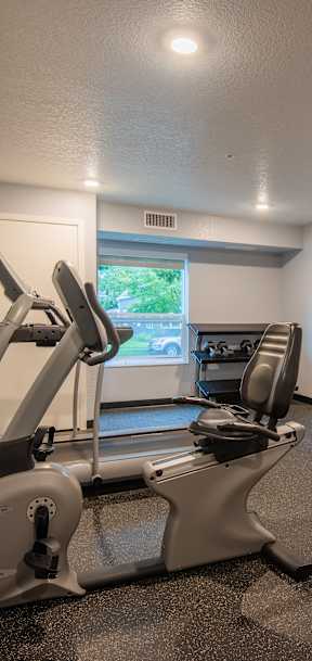 A gym room with treadmills, exercise bikes, and a television.