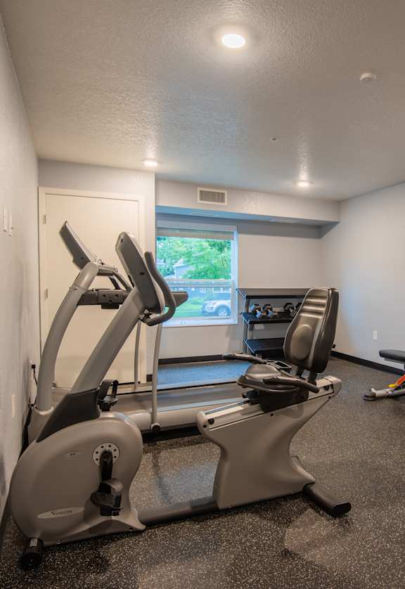 A gym room with treadmills, exercise bikes, and a television.