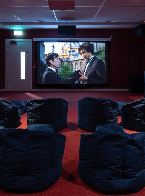 a screening of a movie on a projector screen in a room with chairs