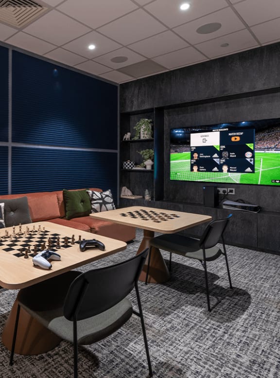 a room with tables and chairs and a soccer game on a tv