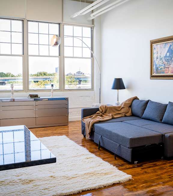 A living room with a grey couch, a black coffee table, and a white rug.